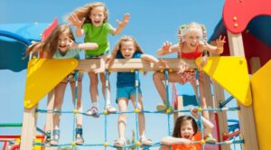 Children playing on colorful jungle gym at playground under blue sky.