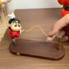 Toy figurine on wooden base with interactive skipping rope, featuring cute character design for desk decor.